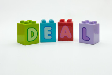 DEAL alphabet on colorful building blocks isolated on a white background. Concept of toy, education, motivation, planning and hope