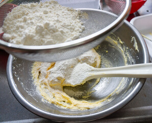 焼き菓子の生地に小麦粉を振るって入れている