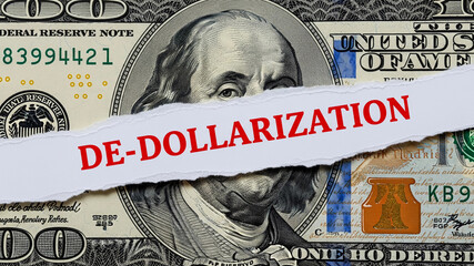 A torn strip of paper with the word "DE-DOLLARIZATION" lies over a hundred-dollar bill, symbolizing the economic trend of shifting away from the US dollar.