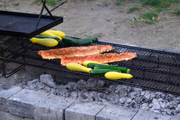 King salmon filets with teriyaki sauce and sesame seeds grilling on an outdoor barbeque pit, along...