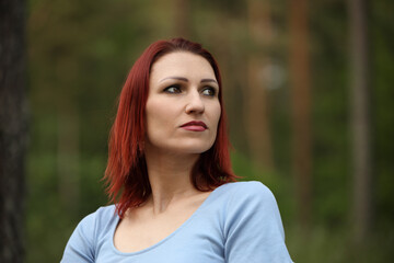 Fototapeta premium red-haired woman posing outdoors in green nature