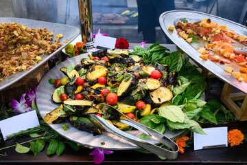Grilled and sliced green and yellow zucchini, along with small heirloom tomatoes and fresh basic on...