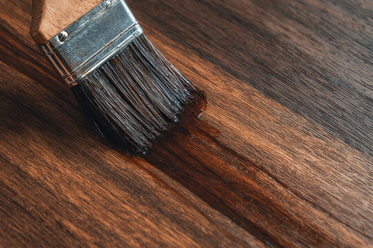 applying shellac over stian in wood table with a brush. AI generative.