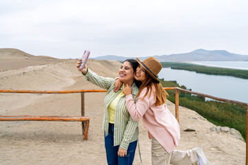 Tourists taking selfie at cerro blanco sand dune with paracas national reserve in background