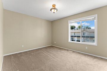 Large empty room with a window and a light fixture