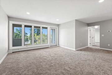 Large, empty living room with a window and a door