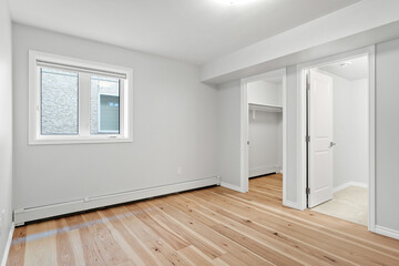 Large, empty room with a window and a closet