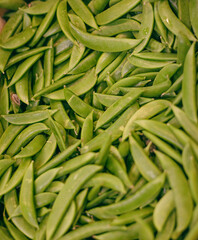 A close-up view of numerous fresh snap peas piled together, showcasing their vibrant green color and natural texture. 