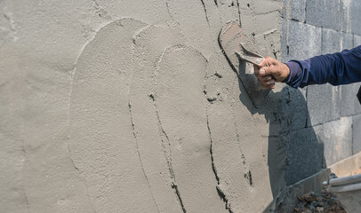 Hand worker man holding handle trowel equipment plaster cement wall background, Mortar grey...
