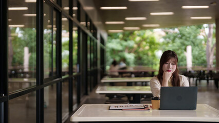 Asian adult woman remote work laptop outdoor cafe campus quiet setting professional study business project