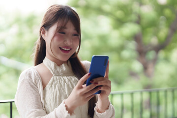 Asian young adult woman freelancer happy smile use mobile phone outdoor connect digital communication lifestyle nature background