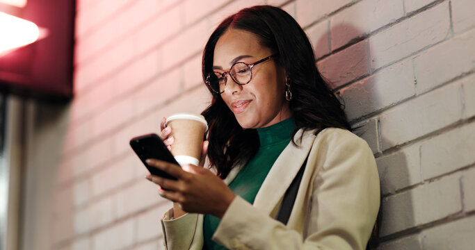 Business woman, phone and coffee in city, night and smile with contact, meme or chat on web by wall. Person, smartphone and drink in town with notification, mobile app and social media in Mexico