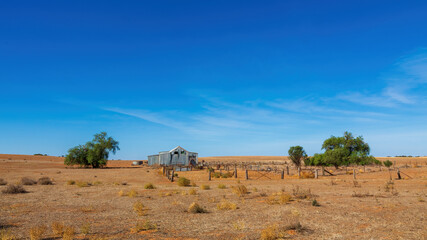 A classic corrugated iron shearing shed with adjoining timber and wire yards stands in the rural Victorian landscape, embodying Australia’s pastoral heritage. 
