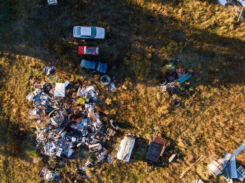 Aerial overhead view of piled of junk and old metal in grassy farm paddock