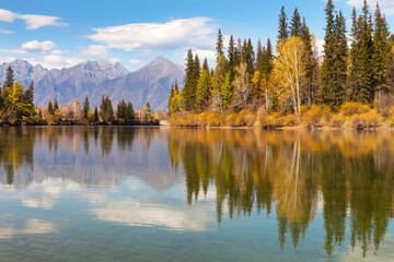 Beautiful autumn landscape with yellowed trees on banks of Irkut River and Eastern Sayan Mountains. Autumn travels. Natural seasonal background. Siberia, Baikal region, Buryatia, Tunka foothill Valley