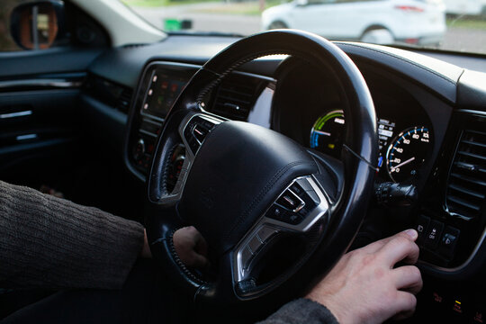 mans hands pressing buttons in hybrid car changing menu settings on vehicle display