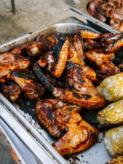 Grilled chicken wings served alongside corn at a lively outdoor gathering