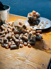 Wine corks and shells scattered on a wooden table in bright sunlight by the water
