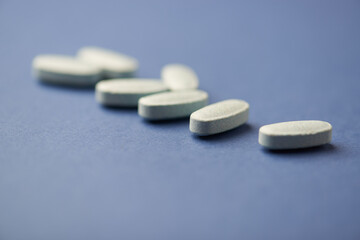 Multivitamin tablets on bright paper background. Close up. Copy space	