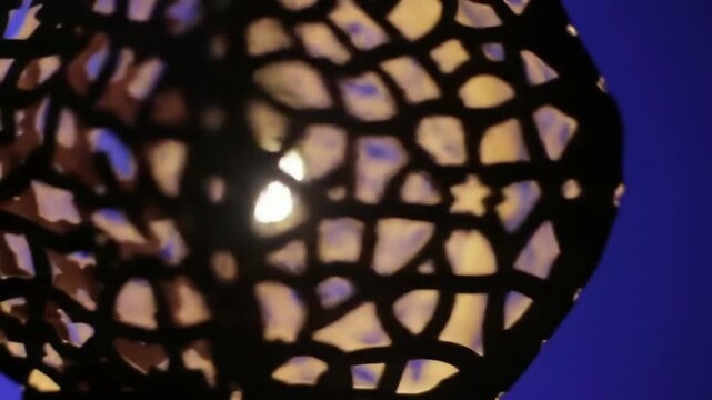 detailed shot of the intricate paper cuts on an Akash Kandil, glowing from within.