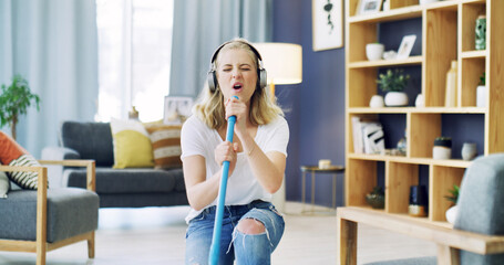 Home, cleaning and woman with broom, singing and dancing with headphones, song and hygiene. Apartment, radio and person in lounge, music and streaming audio with energy, housekeeping and karaoke