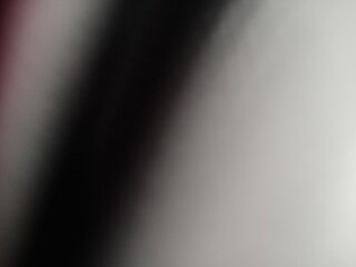 A striking abstract composition featuring a bold diagonal band of deep black against a softly illuminated backdrop creating a sense of dynamic contrast and visual depth.