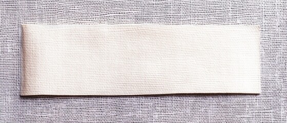Blank, off-white fabric tag on a gray linen fabric