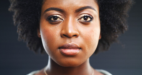 Serious, black woman and portrait with stare in studio for awareness on a dark background. Face, female person or African model with facial expression, afro or features for empowerment or confidence