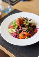 A bowl of fancy salad served on a white plate