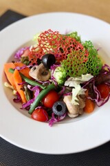 A bowl of fancy salad served on a white plate