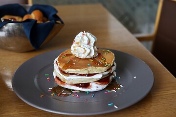 Pancake with maple syrup & honey with cream and other toppings on a table 
