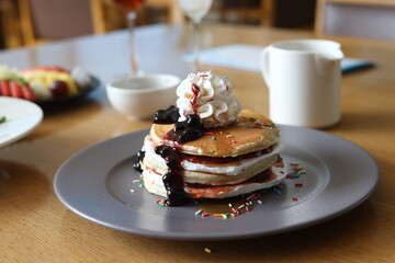 Pancake with maple syrup & honey with cream and other toppings on a table 