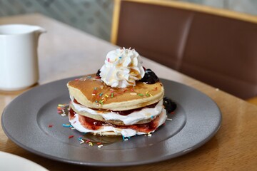 Pancake with maple syrup & honey with cream and other toppings on a table 