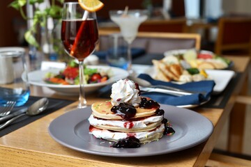 Pancake served with maple syrup and whipped cream on top and other garnishing 