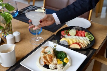 Different kind of food served in a fancy restaurant including fruits, salad and grilled chicken