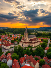 Fototapeta premium Pannonhalma, Hungary - Aerial view of the town of Pannonhalma with the beautiful Millenary Benedictine Abbey of Pannonhalma (Pannonhalmi Apatsag) and dramatic sunset sky at summertime