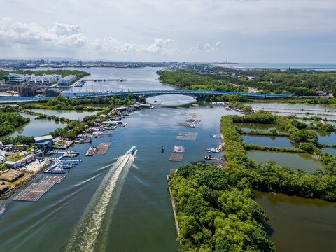 Aerial view of Yuguang Bridge over Kunshen Lake, with boats, oyster farms, and the Yuguang Island coastline on a sunny day. Tainan, Taiwan.