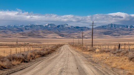 A long dirt road stretches through a dry, open plain toward distant mountains under a bright blue sky with scattered clouds