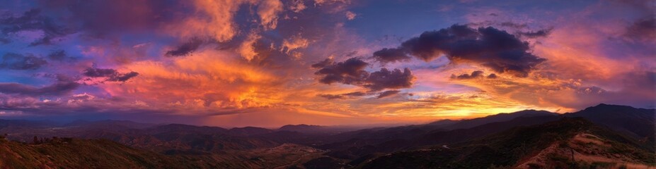 Fototapeta premium Panoramic sunset over mountain ranges, vibrant colors, dramatic clouds