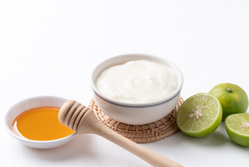 Yogurt, lime and honey on white background