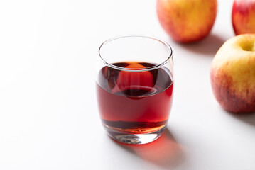 Glass of apple cider with red apple fruit on white background