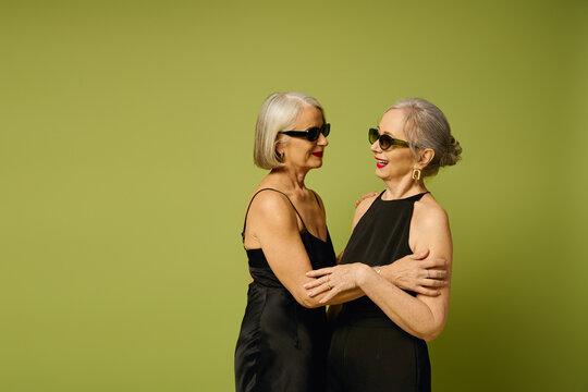 Elegant mature couple sharing a romantic moment in fashionable attire against a soft green backdrop