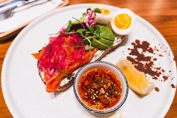 Salmon with avocado and eggs open sandwich, colorful vegetables