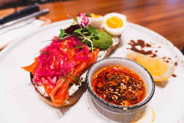 Salmon with avocado and eggs open sandwich, colorful vegetables