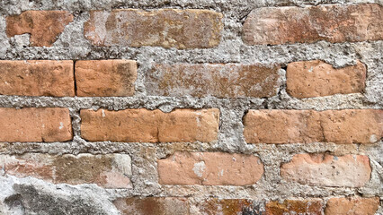 Close-up of an old, rough brick wall with cement mortar. The weathered texture and natural imperfections of the bricks create a rustic and vintage backdrop. Ideal for architectural, construction, 