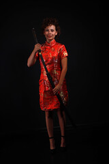 Young brunette woman in red dress with traditional Japanese katana sword low key full length portrait