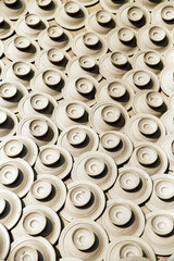 An artistic display of numerous handcrafted ceramic pottery pieces evenly arranged and lit by natural sunlight, showcasing traditional craftsmanship and detailing.
