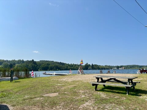 Lakeside picnic area with dock, chairs, and lifeguard stand