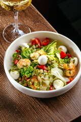 Caesar salad with shrimp and a glass of wine