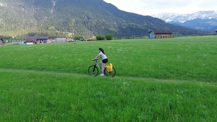 Cycling on green field near snow peaks